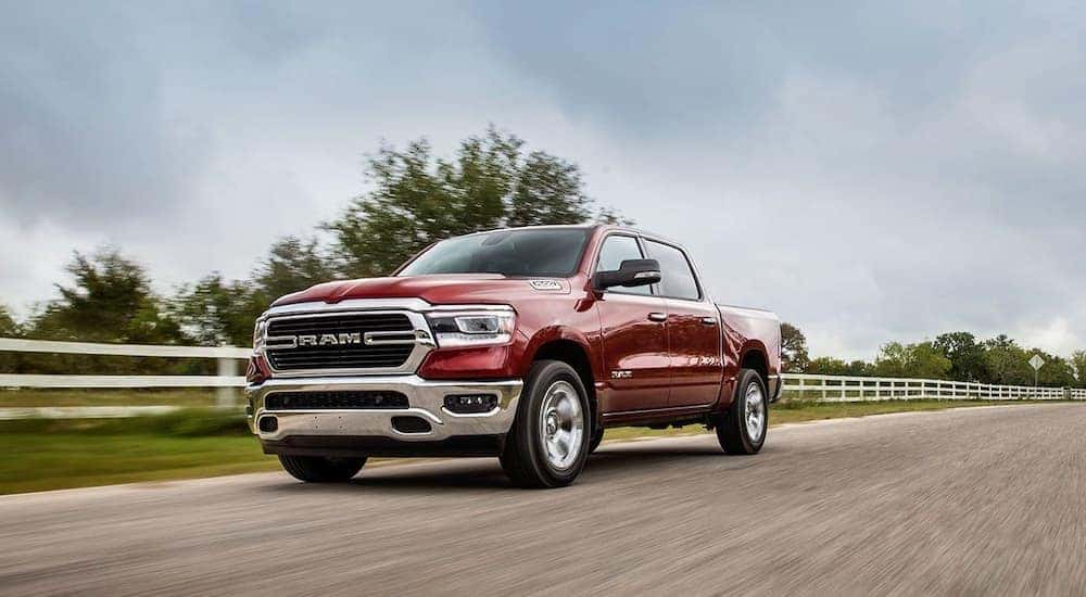 A red 2023 Ram 1500 is shown driving on a road.