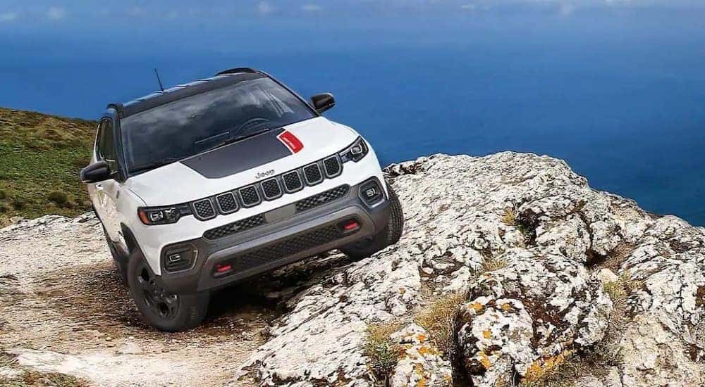 A white and black 2023 Jeep Compass Trailhawk is shown parked near a cliff.