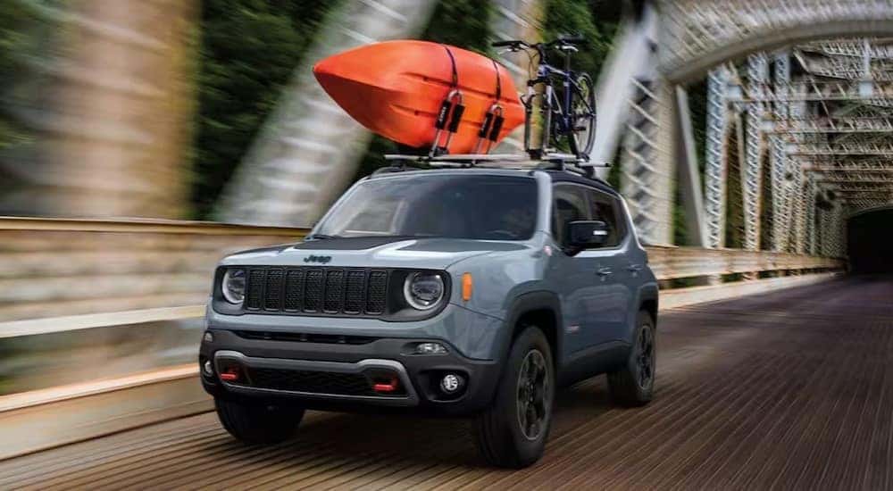 A gray 2023 Jeep Renegade is shown driving on a bridge after visiting an SUV dealer.