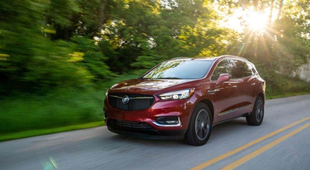 A red 2020 Buick Enclave Sport Touring is shown driving on a highway.