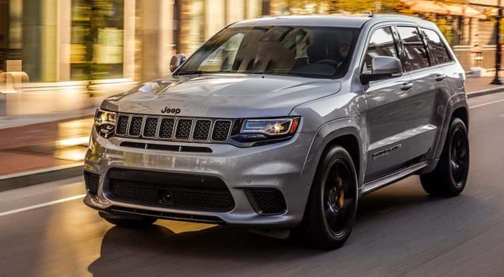A silver 2020 Jeep Grand Cherokee is shown driving on a city street.