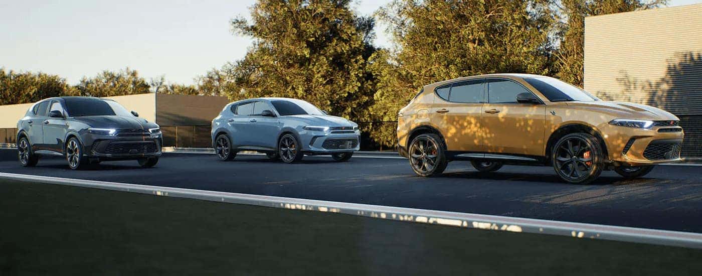 A yellow 2023 Dodge Hornet is shown driving alongside a blue 2023 Dodge Hornet and black 2023 Dodge Hornet.