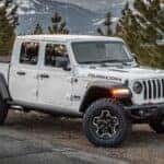A white 2024 Jeep Gladiator Rubicon is shown from the front at an angle after leaving a used truck dealer.
