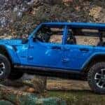 A blue 2024 Jeep Wrangler 4xe is shown driving off-road after viewing a Jeep Wrangler 4xe for sale near Cincinnati.