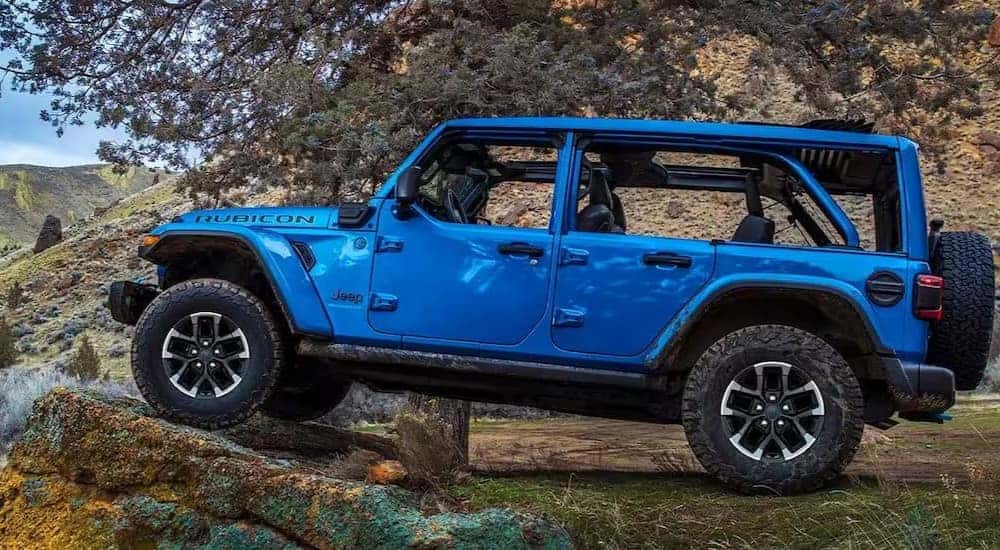 A blue 2024 Jeep Wrangler 4xe is shown driving off-road after viewing a Jeep Wrangler 4xe for sale near Cincinnati.