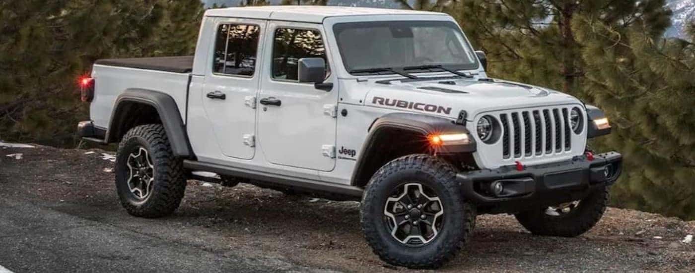 A white 2023 Jeep Gladiator Rubicon is shown parked near a road on a mountain.
