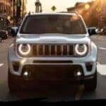 A white 2023 Jeep Renegade is shown driving on a crosswalk after visiting a Jeep dealer.