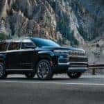 A black 2024 Grand Wagoneer is shown driving near a mountain.