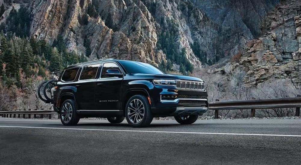 A black 2024 Grand Wagoneer is shown driving near a mountain.