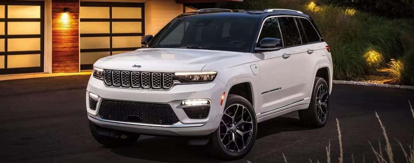 A white 2024 Jeep Grand Cherokee 4xe is shown parked on a driveway after visiting a Jeep dealer.