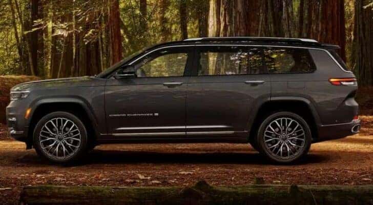 A gray 2024 Jeep Grand Cherokee is shown parked in a forest.