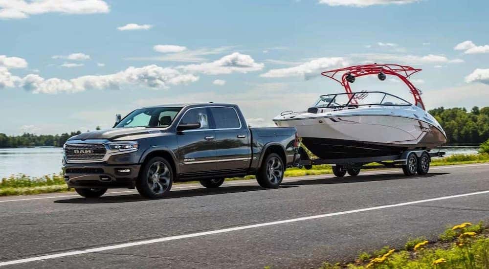 A black 2024 Ram 1500 is shown towing a boat after visiting a Ram dealer.