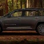 Side view of a grey 2024 Jeep Grand Cherokee L parked in the woods.
