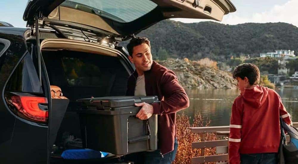 A person is shown loading a cooler into a 2024 Chrysler Pacifica Hybrid after visiting a Chrysler dealer.