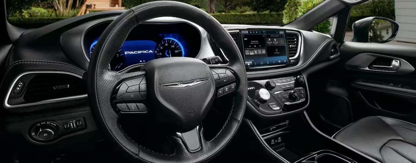A black steering wheel and dashboard are shown in the interior of a 2024 Chrysler Pacifica.