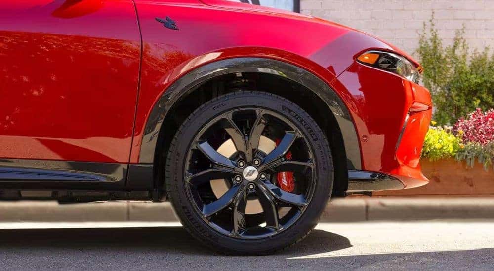 A close up shows a black wheel on a red 2024 Dodge Hornet Scat Pack.