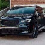 A black 2024 Chrysler Pacifica is shown parked on a driveway.
