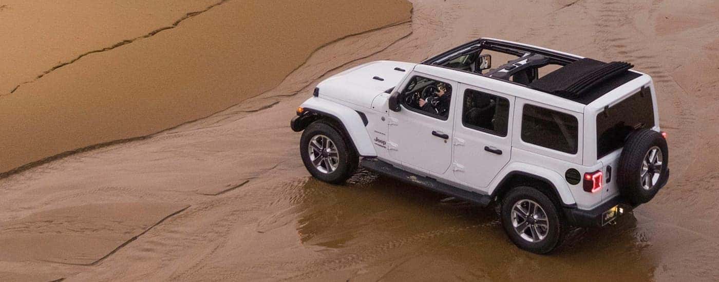 A white 2020 Jeep Wrangler Unlimited parked on a shore.