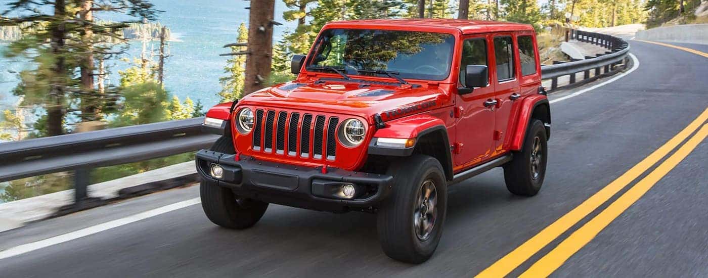 A red 2024 Jeep Wrangler Rubicon Unlimited driving around a bend.