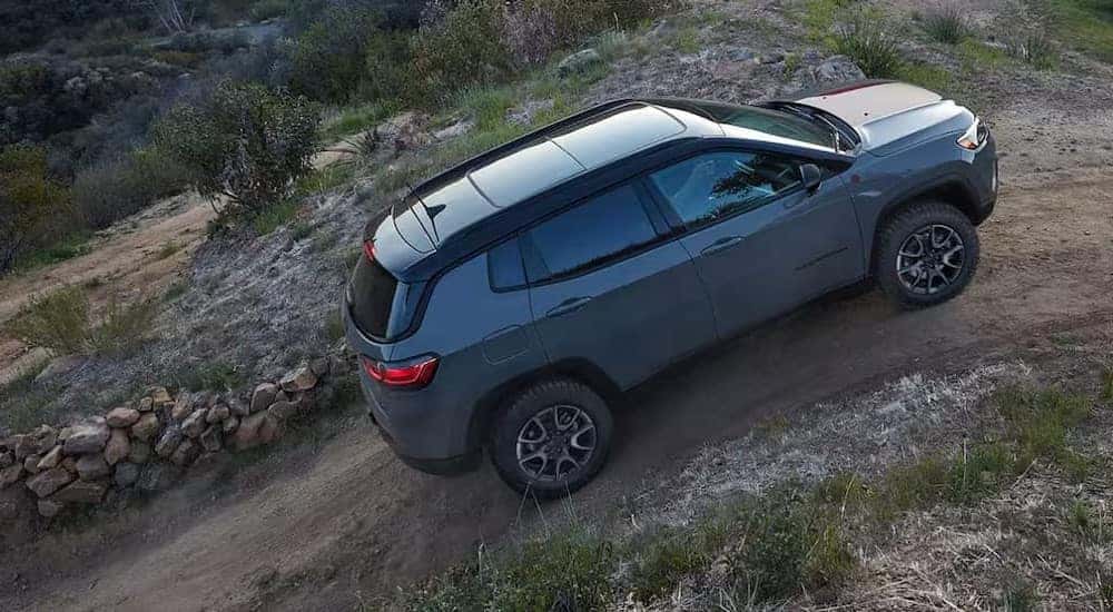 A gray 2024 Jeep Compass is shown driving uphill.