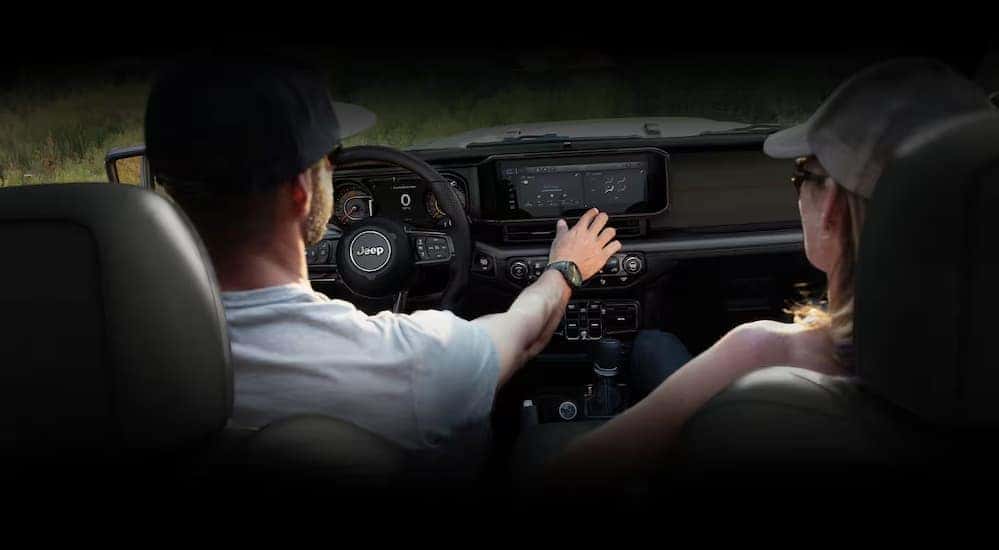 A person is shown touching the infotainment screen in a 2024 Jeep Gladiator for sale.