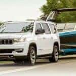 A white 2024 Jeep Wagoneer is shown towing a boat to a Jeep dealer near Fairfield.