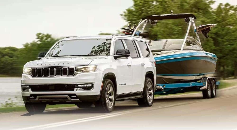 A white 2024 Jeep Wagoneer is shown towing a boat to a Jeep dealer near Fairfield.