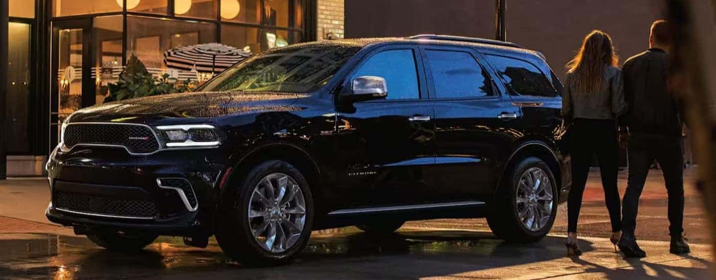 A black 2024 Dodge Durango is shown parked near two people walking.