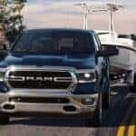 A blue 2024 Ram 1500 is shown towing a boat.