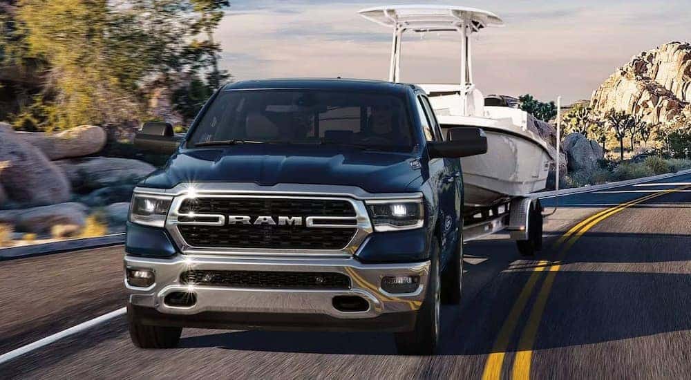 A blue 2024 Ram 1500 is shown towing a boat.