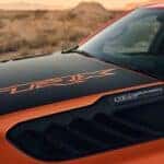 The TRX decal on the hood of an orange 2024 Ram 1500 TRX Final Edition.