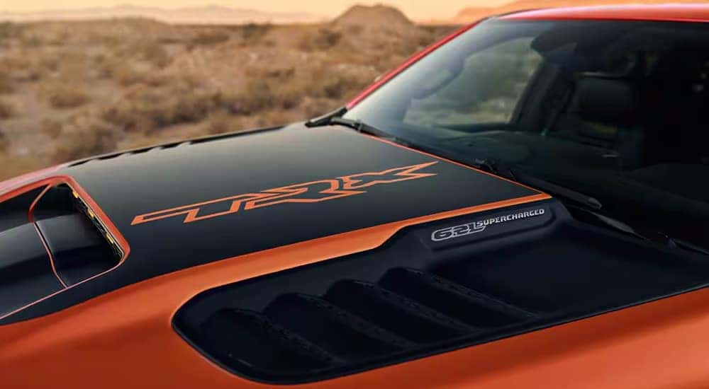 The TRX decal on the hood of an orange 2024 Ram 1500 TRX Final Edition.