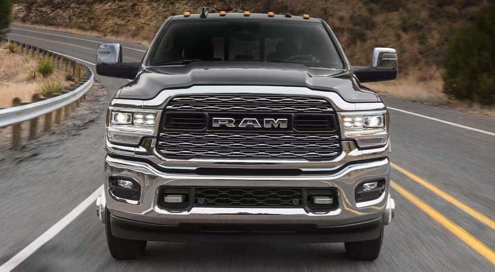 A black 2024 Ram 3500 Limited is shown driving on a highway after viewing a Ram 3500 for sale.