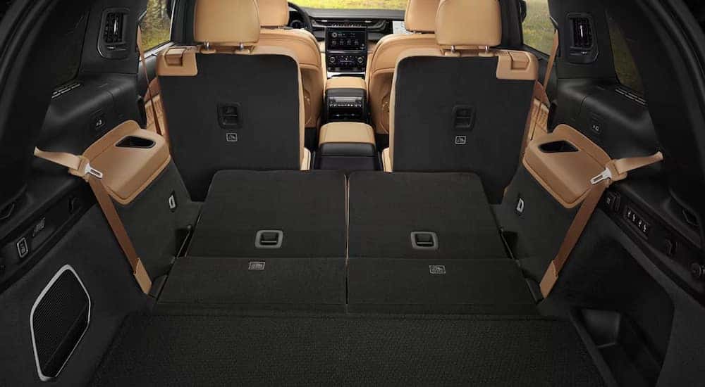 The brown interior of a 2024 Jeep Grand Cherokee L for sale is shown from the rear hatch.