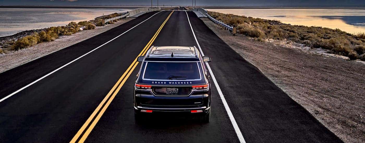 Aerial view of a blue 2023 Jeep Grand Wagoneer L driving on an open road.