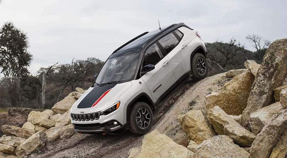 A white 2025 Jeep Compass TrailHawk is shown from the side while off-roading.