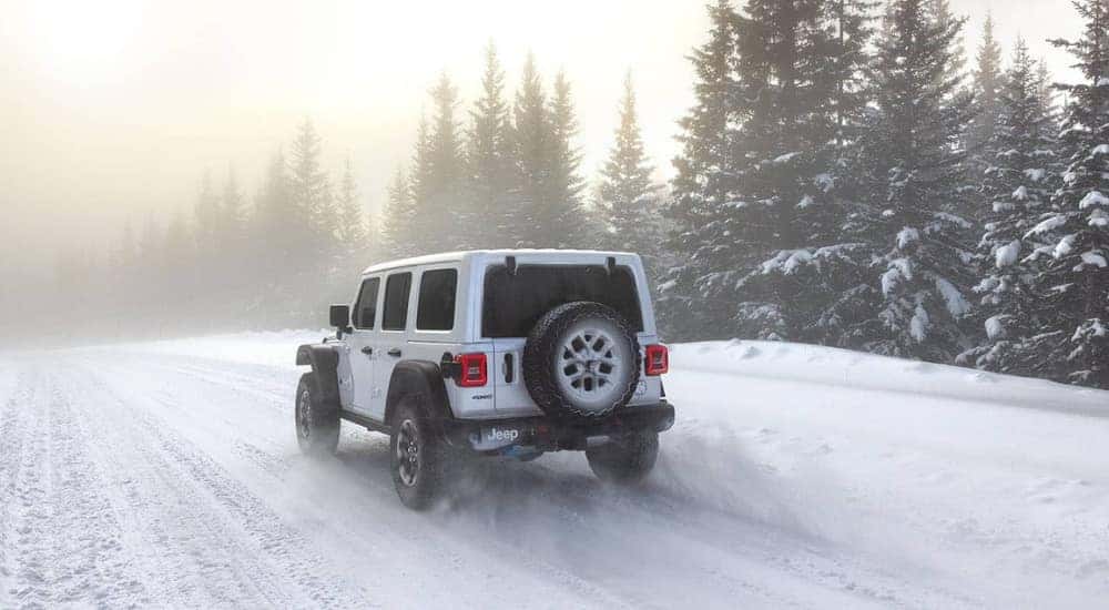 A white 2025 Jeep Wrangler 4xe is shown on a snowy trail.