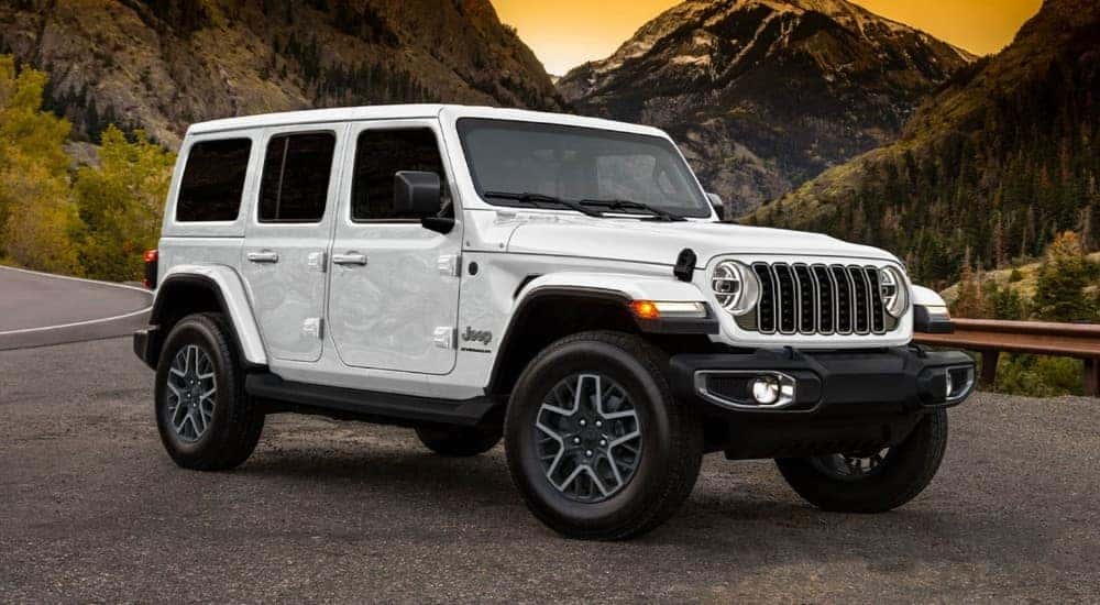 A white 2025 Jeep Wrangler Unlimited is shown parked on a gravel lot.