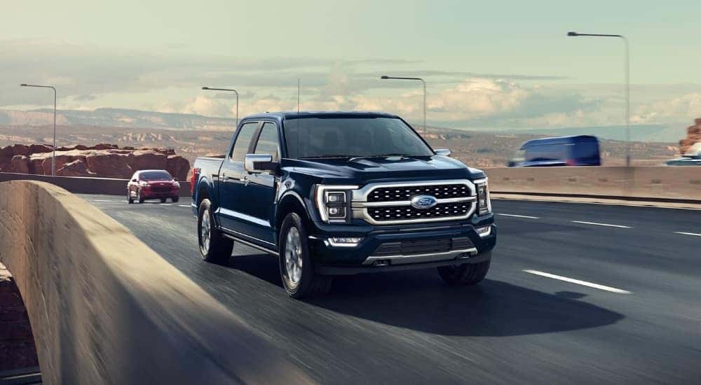 A dark blue 2023 Ford F-150 is shown driving on a highway.