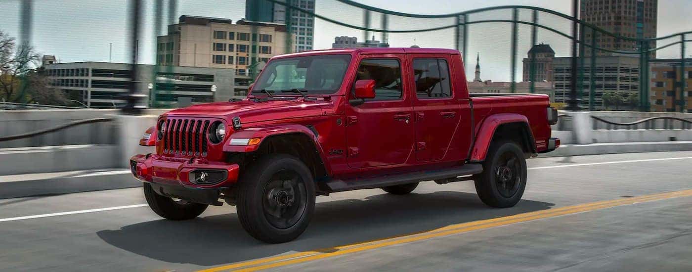 A red 2021 Jeep Gladiator is shown driving to view used trucks for sale near Cincinnati.