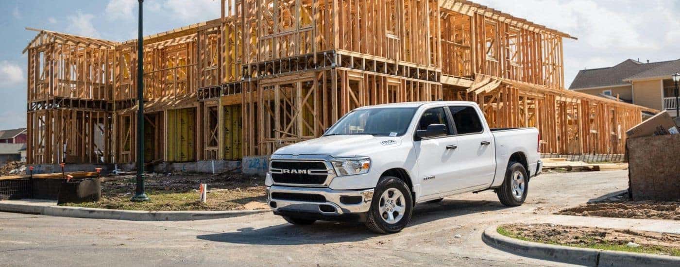 A white 2022 Ram 1500 is shown driving near a construction site.