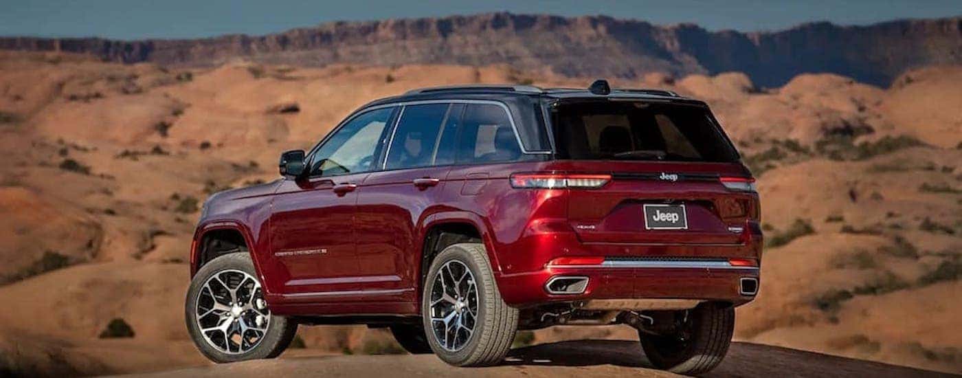 A red 2024 Jeep Grand Cherokee is shown from the rear at an angle.
