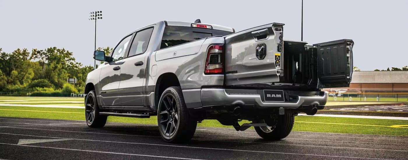 A silver 2024 Ram 1500 is shown parked on a track with the tailgate open.