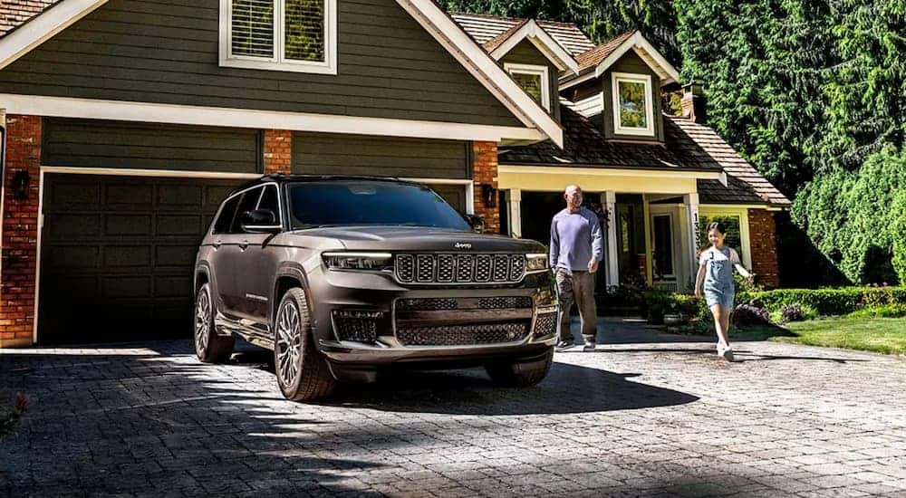 A family is walking towards a grey 2025 Jeep Grand Cherokee.