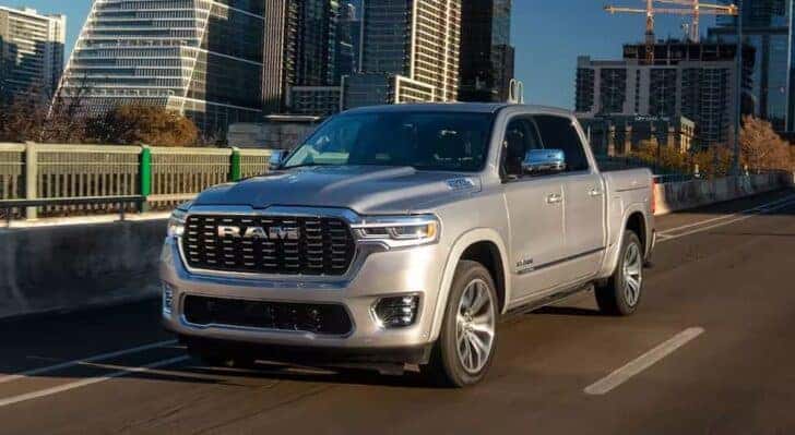 A silver 2025 Ram 1500 for sale in Florence is shown driving on a bridge.
