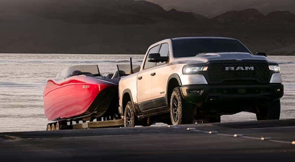 A silver 2025 Ram 1500 for sale in Florence is shown from the front while loading a boat.