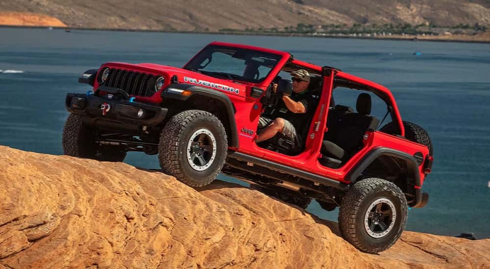 A red 2025 Jeep Wrangler Rubicon is shown off-roading.