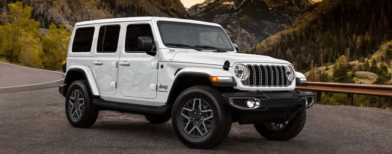 A white 2025 Jeep Wrangler Sport is parked on pavement.