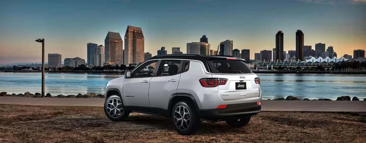 A white 2025 Jeep Compass is shown parked near a city.
