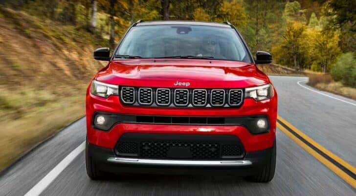 A red 2025 Jeep Compass for sale in Florence is shown driving on a highway.